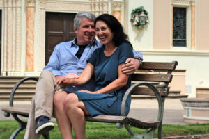 A middle-aged couple sitting on a park bench.